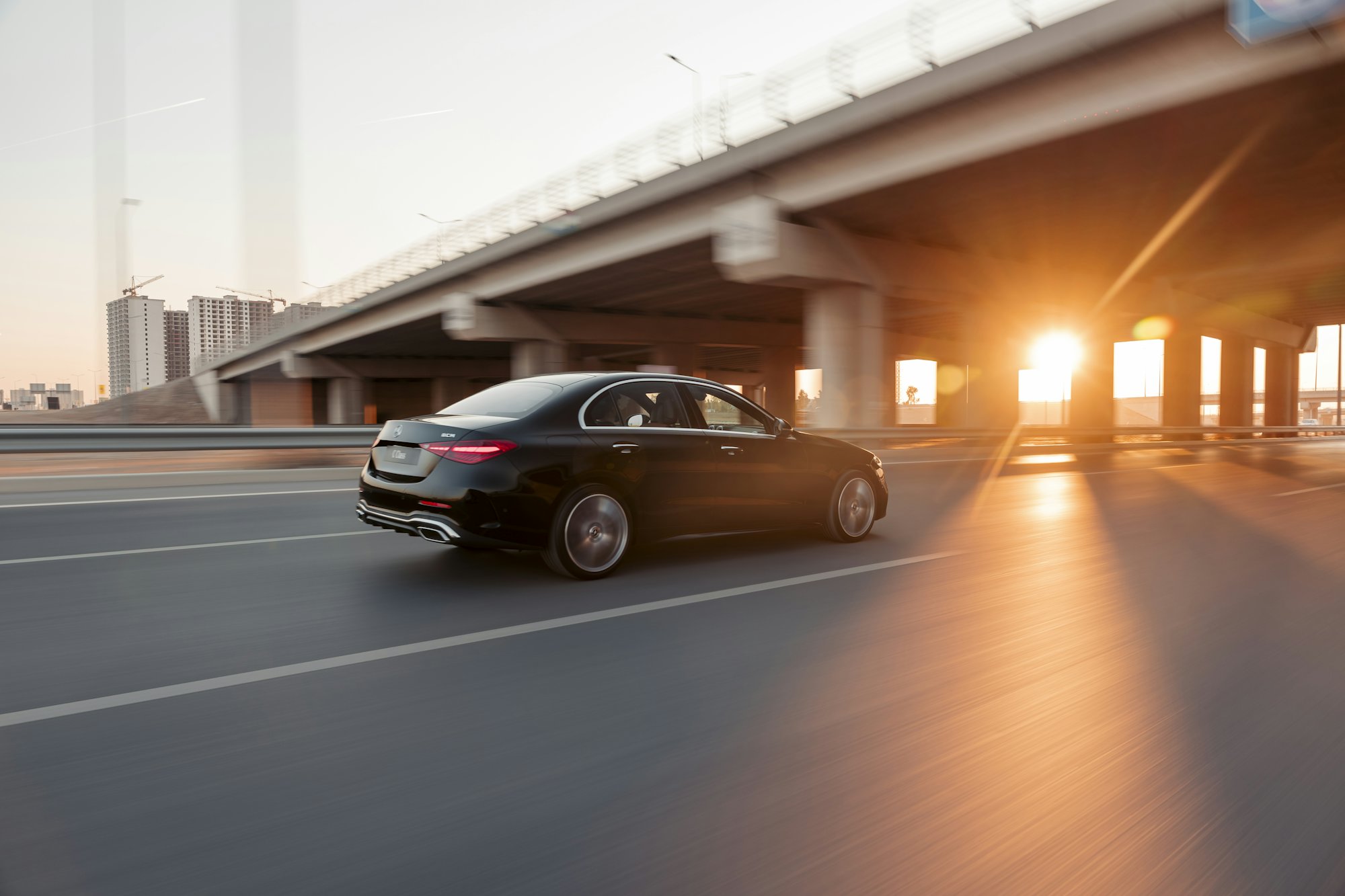 A black executive car driving at sunset